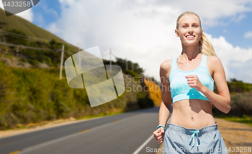 Image of happy woman running nearby road over big sur hills