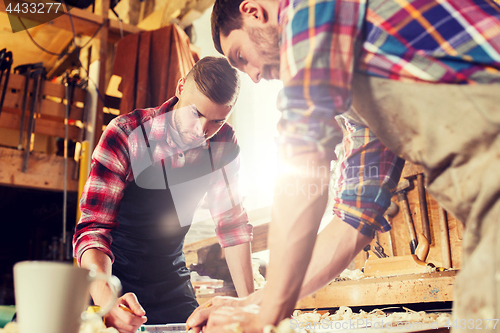 Image of carpenters with ruler and blueprint at workshop