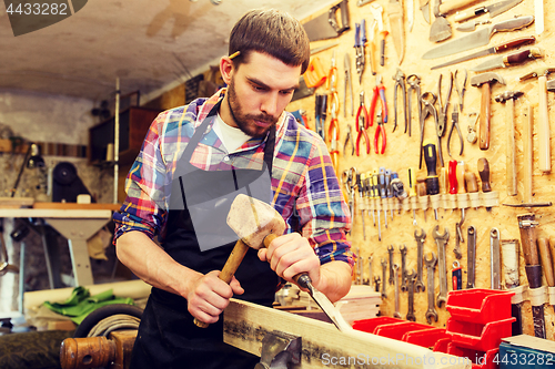 Image of carpenter with wood, hammer and chisel at workshop