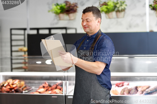 Image of seller at fish shop writing to clipboard