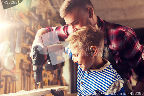 Image of father and son with drill working at workshop