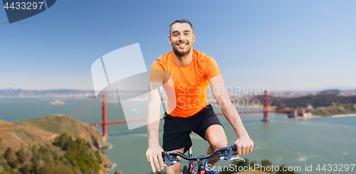 Image of happy man riding bicycle over golden gate bridge