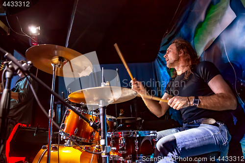 Image of Drummer playing on drum set on stage.