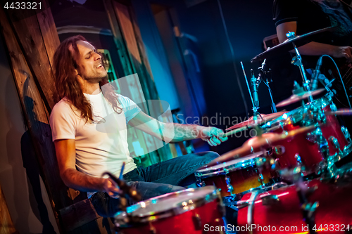 Image of Drummer playing on drum set on stage.