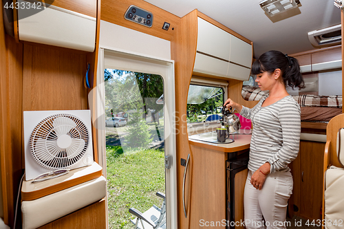 Image of Woman cooking in camper, motorhome interior