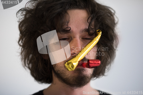 Image of Portrait of a man in party hat blowing in whistle