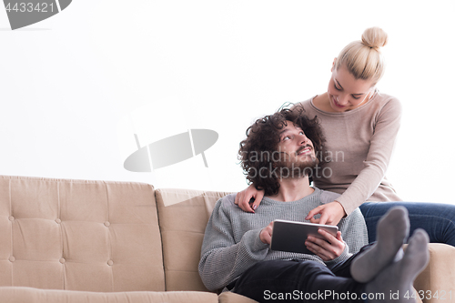 Image of couple relaxing at  home with tablet computers