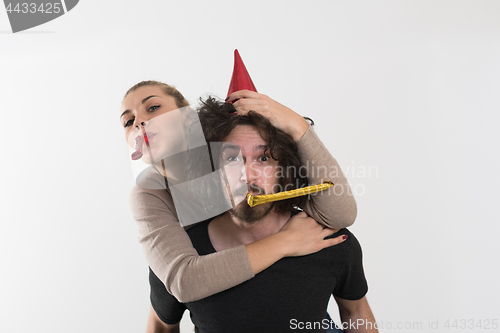 Image of couple in party hats blowing in whistle