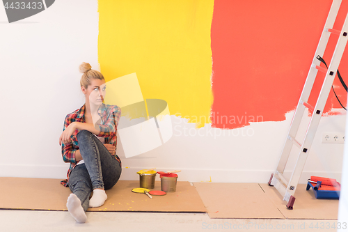 Image of young female painter sitting on floor