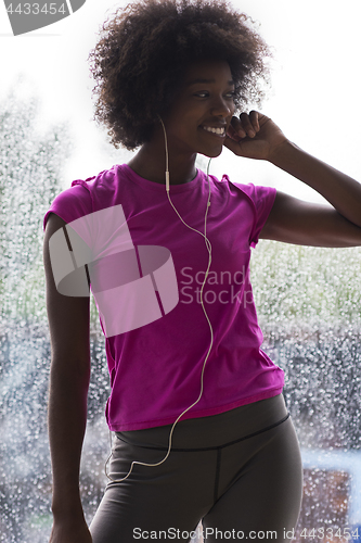 Image of portrait of young afro american woman in gym while listening mus