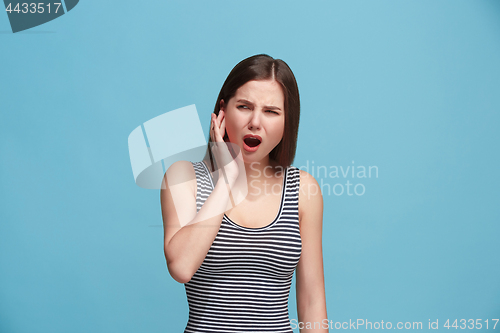 Image of The Ear ache. The sad woman with headache or pain on a blue studio background.