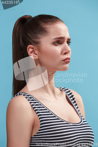 Image of The young woman is looking sad on the blue background.