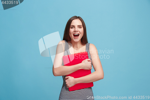 Image of Businesswoman hugging laptop on blue studio