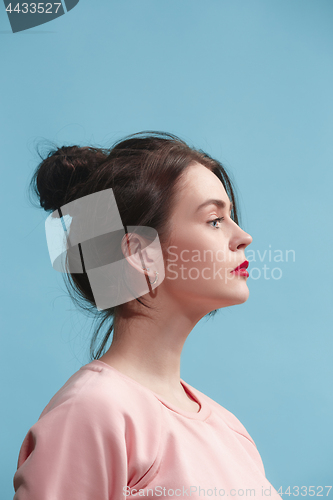 Image of The serious business woman standing against blue background.