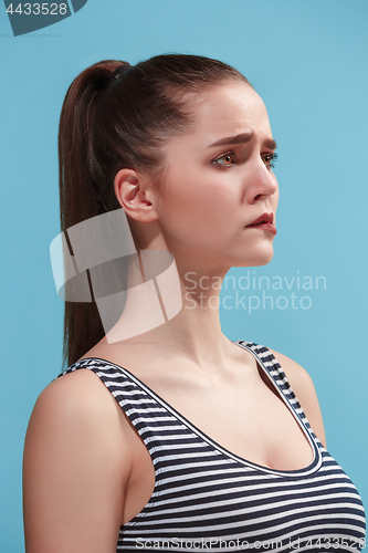 Image of The young woman is looking sad on the blue background.