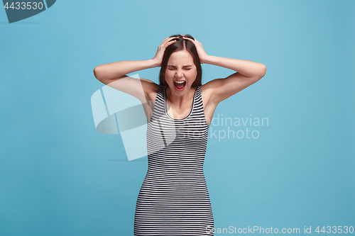 Image of The young emotional angry woman screaming on blue studio background