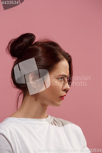 Image of The serious business woman standing against pink background.