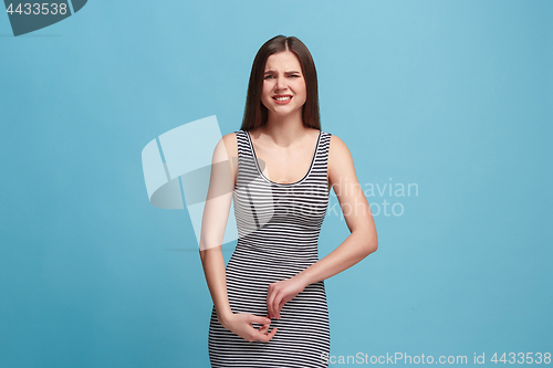 Image of The awkward woman standing and looking at camera against blue background.