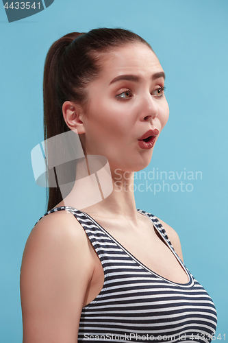 Image of The young woman is looking surprising on the blue background.