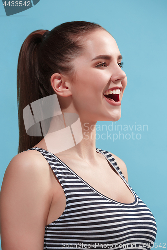 Image of The happy woman standing and smiling against blue background.