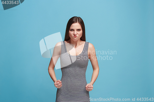 Image of Portrait of an angry woman looking at camera isolated on a blue background