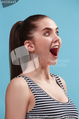 Image of The happy woman standing and smiling against blue background.