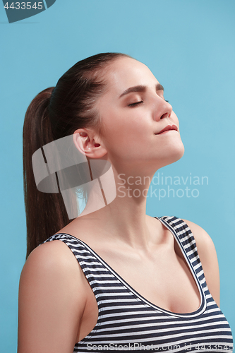 Image of The young woman is looking satisfy on the blue background.