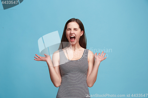 Image of The young emotional angry woman screaming on blue studio background