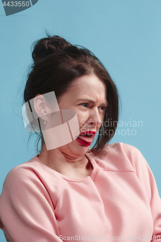 Image of Young woman with disgusted expression repulsing something, isolated on the blue