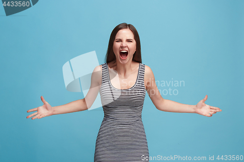 Image of The young emotional angry woman screaming on blue studio background