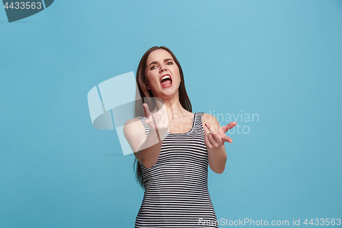 Image of Portrait of an angry woman looking at camera isolated on a blue background