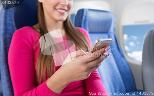 Image of close up of woman sitting in plane with smartphone