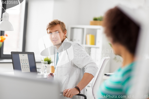 Image of happy creative workers with laptops at office