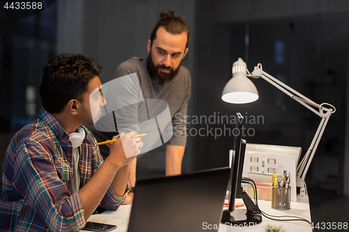 Image of creative team with computer working late at office