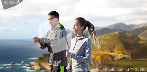 Image of couple with fitness trackers running outdoors