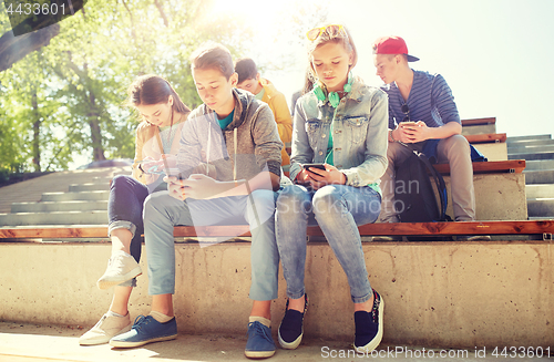 Image of group of teenage friends with smartphones outdoors