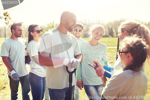 Image of group of volunteers with tree seedlings in park