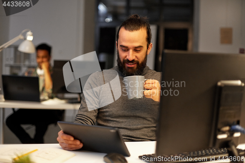 Image of man with tablet pc drinking coffee at office
