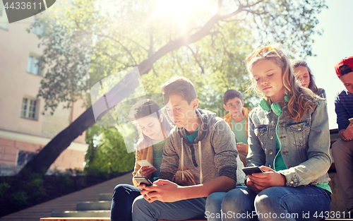 Image of group of teenage friends with smartphones outdoors