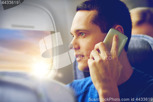 Image of young man calling on smartphone in plane