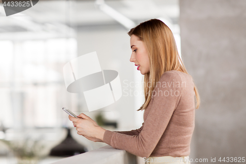 Image of happy businesswoman with smartphone at office