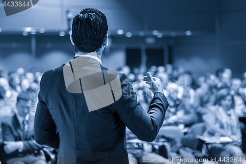 Image of Public speaker giving talk at business event.