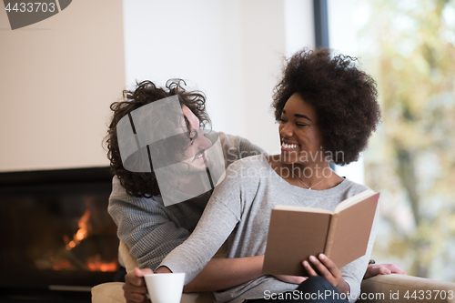 Image of multiethnic couple hugging in front of fireplace