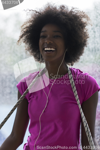 Image of portrait of young afro american woman in gym while listening mus