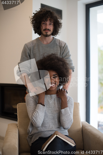 Image of multiethnic couple hugging in front of fireplace