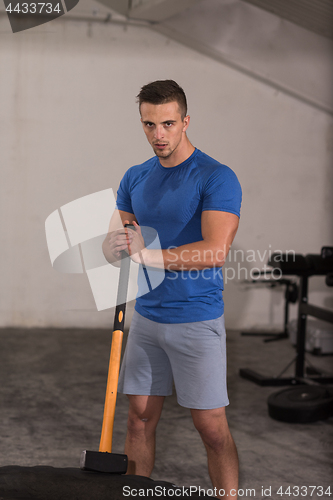 Image of man workout with hammer and tractor tire