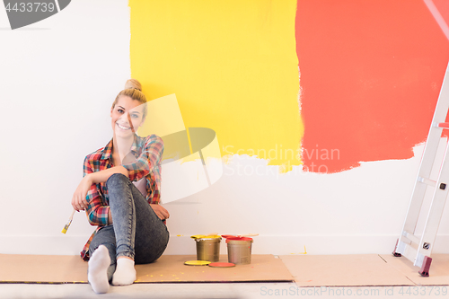 Image of young female painter sitting on floor