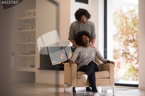 Image of multiethnic couple hugging in front of fireplace