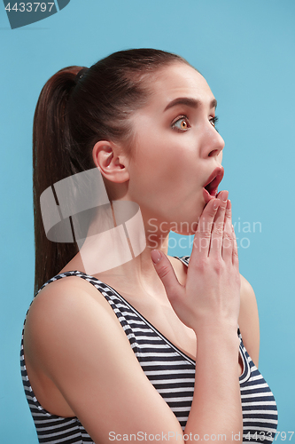 Image of The young woman is looking surprising on the blue background.