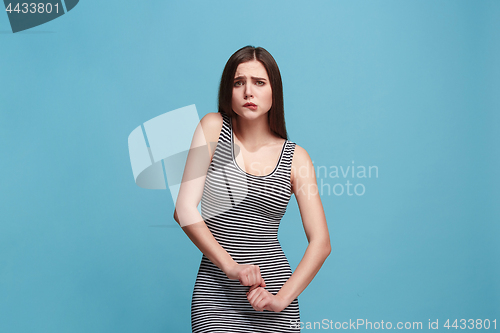 Image of The awkward woman standing and looking at camera against blue background.